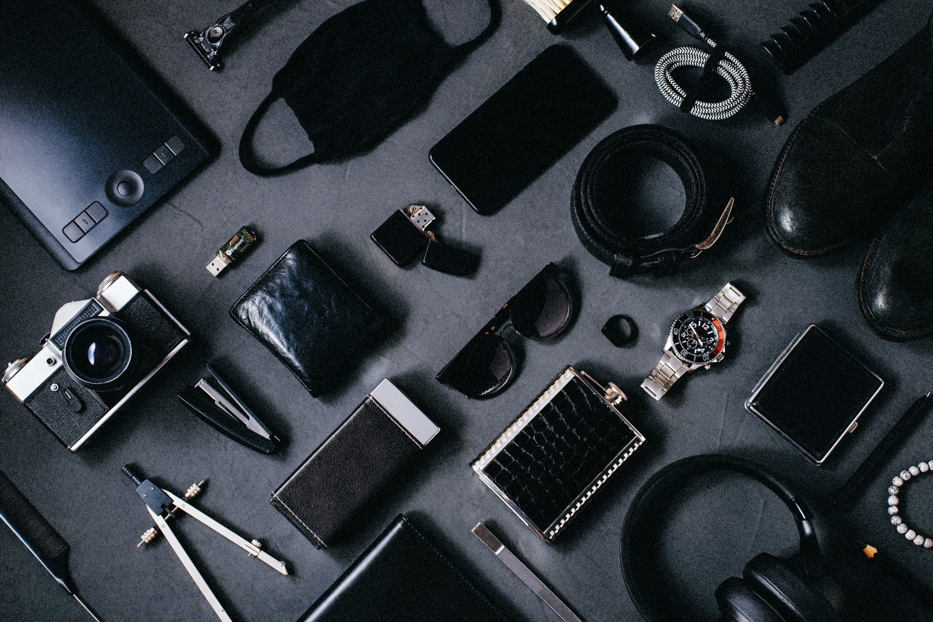 Flat-lay of everyday carry items with a steel dive watch on a slate surface