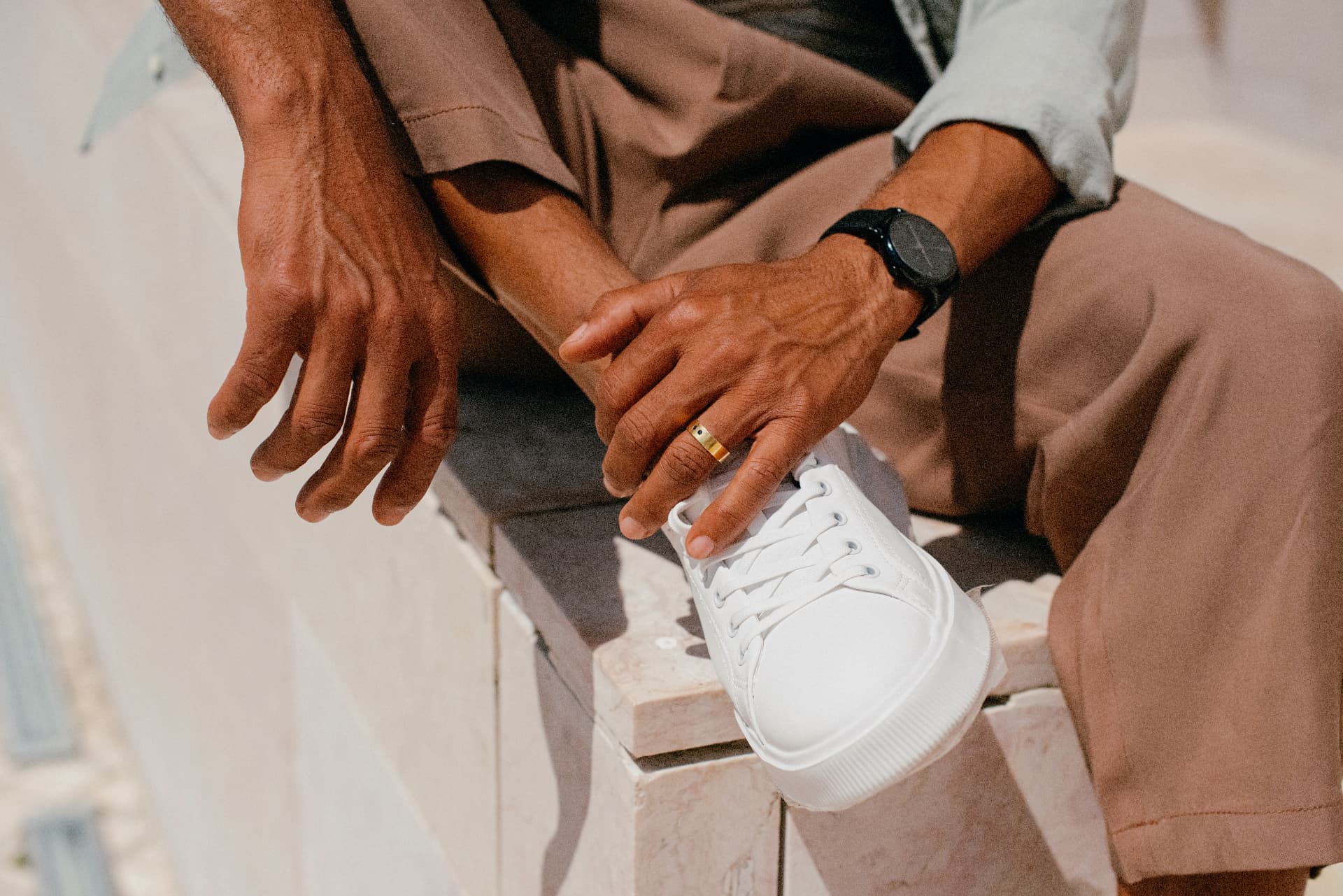 A man wearing a minimal black watch with relaxed tailoring and white sneakers